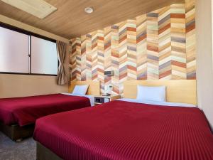 una camera d'albergo con due letti con lenzuola rosse di Hotel New Gaea Yakuin a Fukuoka