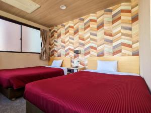 a hotel room with two beds with red sheets at Hotel New Gaea Yakuin in Fukuoka