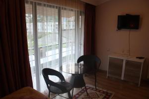 um quarto com uma mesa e cadeiras de vidro e uma janela em Sunny City em Borjomi
