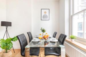 una sala da pranzo con tavolo in vetro e sedie nere di Central London Soho Suite - CityApartmentStay a Londra