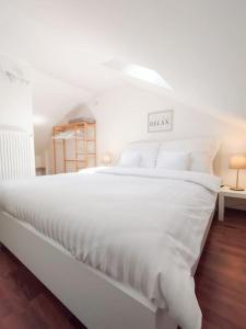 1 cama blanca grande con sábanas y almohadas blancas en Belvárosi allódium 2., en Szentendre