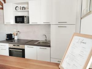 eine Küche mit weißen Schränken und einem Waschbecken in der Unterkunft Belvárosi allódium 2. in Szentendre