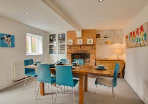 a dining room with a wooden table and blue chairs at Peddars Rest in Sedgeford