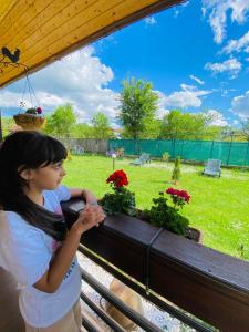 a young girl standing next to a bench with flowers at Serenity Garden Villa in Runcu