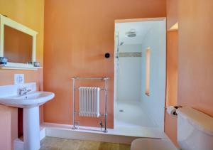 uma casa de banho com um lavatório branco e um chuveiro em The Magazine em Sedgeford