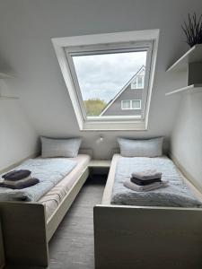 2 Betten in einem Zimmer mit Fenster in der Unterkunft Ferienhaus Heyder in Norderney