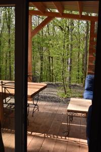 - une terrasse couverte avec une table de pique-nique et des bancs dans l'établissement Gite cocon dans la forêt, à Philippeville