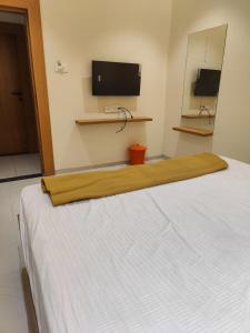 białe łóżko w pokoju z telewizorem z płaskim ekranem w obiekcie Hotel Bhaiji Executive w mieście Nander
