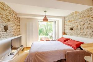 ein Schlafzimmer mit einem Bett und einer Ziegelwand in der Unterkunft Moulin du Buis - Bain nordique, charme et détente in Saint-Sorlin-en-Bugey