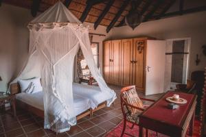 Schlafzimmer mit einem Bett mit Moskitonetz in der Unterkunft Ohorongo Safari Lodge in Kamanjab