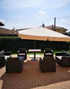 un patio con mesa, sillas y sombrilla en certe notti langhe, en Salmore