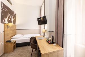 a hotel room with a bed and a desk with a computer at City Hotel Ring in Budapest
