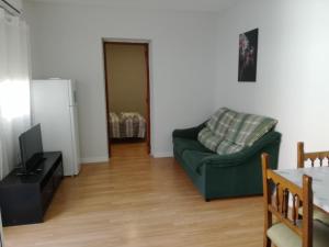 uma sala de estar com um sofá verde e uma televisão em Home P.C em Getafe