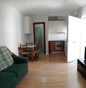 uma sala de estar com um sofá verde e uma cozinha em Home P.C em Getafe