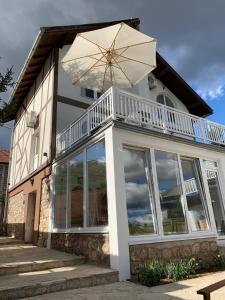 ein Haus mit einem Balkon und einem Sonnenschirm in der Unterkunft Sokograd Loft in Šipovo