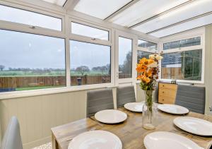 a dining room with a table with flowers in a vase at Sanabrin and Little Brin in Weasenham