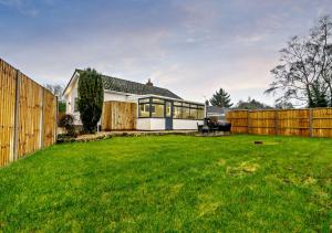 a house with a fence and a green yard at Sanabrin and Little Brin in Weasenham