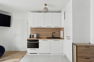 a kitchen with white cabinets and a sink at Chic et minimaliste studio Batignolle/Montmartre by Weekome in Paris