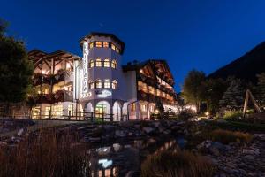 a building with a pond in front of it at night at Kristiania Pure Nature Hotel & Spa in Cogolo