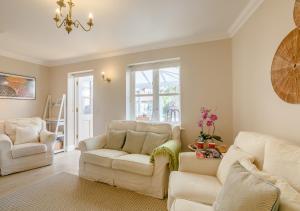 a living room with white furniture and a chandelier at 2 Oaklands Cottage in Holt
