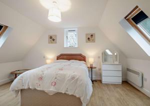 a bedroom with a bed with a white comforter at Little Coach House 