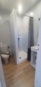 La salle de bains blanche est pourvue d'une douche et de toilettes. dans l'établissement Hôtel L'Oustaou, au Lavandou