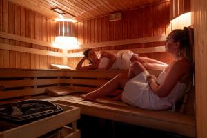 dos personas están sentadas en una sauna en Holimo Hotel, en Stronie Śląskie