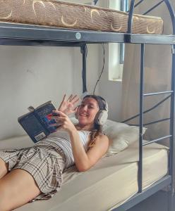 uma mulher com auscultadores deitada num beliche com um portátil em Georgetown Heritage Hostel em George Town