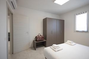 um quarto branco com uma cama e um armário castanho em The Residence 2.0 em Galliate