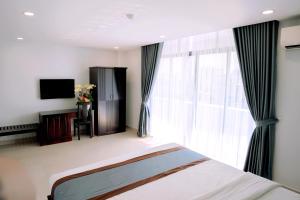 a bedroom with a bed and a large window at Song Tien Hotel in Mỹ Tho