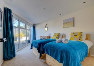 a bedroom with two beds with blue sheets and a window at The Eye in Sheringham