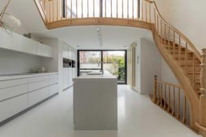 a kitchen with white cabinets and a wooden stairway at Spacious Belle Epoque House with free parking in Ostend