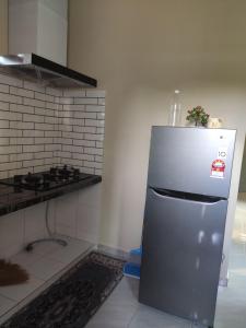 a kitchen with a stainless steel refrigerator and a stove at ABHAR Inap Desa in Alor Setar