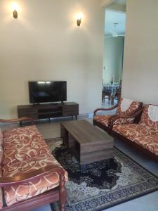 a living room with two couches and a tv at ABHAR Inap Desa in Alor Setar