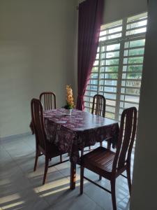 a dining room table with four chairs and a window at ABHAR Inap Desa in Alor Setar