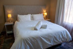 ein großes weißes Bett mit zwei Kissen darauf in der Unterkunft Casa de la Presa 2 in Polokwane