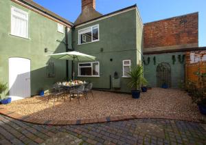 a patio with a table and an umbrella at Carpenters Cottage in Cromer