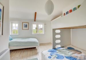 a childs bedroom with a bunk bed and windows at Aurora Cottage in Little Barningham