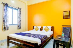 een slaapkamer met een bed en een laptop op een tafel bij SPOT ON Hotel Shree Samarth Lodging in Kolhapur