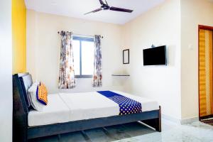 een slaapkamer met een bed en een tv aan de muur bij SPOT ON Hotel Shree Samarth Lodging in Kolhapur