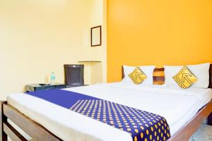 een slaapkamer met een groot bed met blauwe en gele muren bij SPOT ON Hotel Shree Samarth Lodging in Kolhapur
