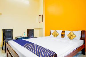 een slaapkamer met een bed met een gele muur bij SPOT ON Hotel Shree Samarth Lodging in Kolhapur