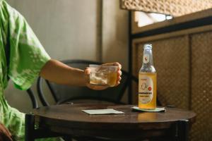 a person holding a glass of beer next to a bottle at ARTOTEL Haniman Ubud in Ubud