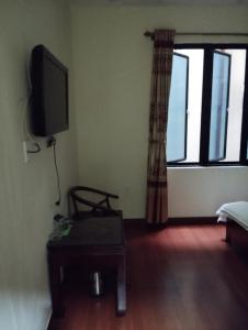 a living room with a tv and a chair and a table at Nhà nghỉ Thành Đạt in Hai Phong