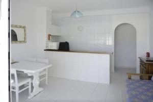 eine weiße Küche mit einer Theke und einem Tisch in der Unterkunft Apartamento Ciel Azul in Cala Llena