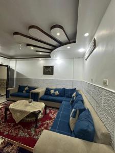 uma sala de estar com sofás azuis e uma mesa em شقة مفروشة للايجار em Irbid