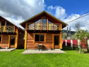een houten huis met een veranda en een groene tuin bij Eco Centr Zrub in Maydan
