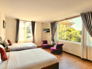 a hotel room with two beds and a large window at Carnival Villa in Da Lat