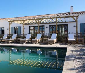 una piscina en un hotel con sillas y pérgola en La Mission - l'île d'Yeu, en Île d'Yeu