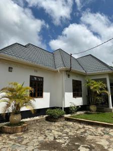 une maison blanche avec un toit noir dans l'établissement Green Living Apartment, à Nkoanrua